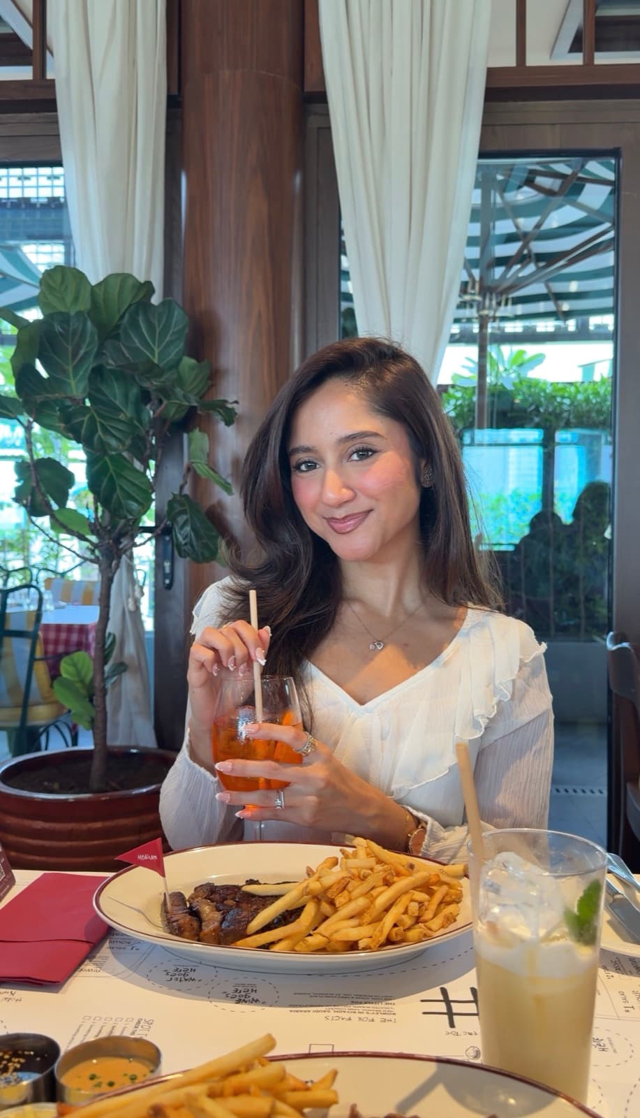 Nikita with a drink at a café table