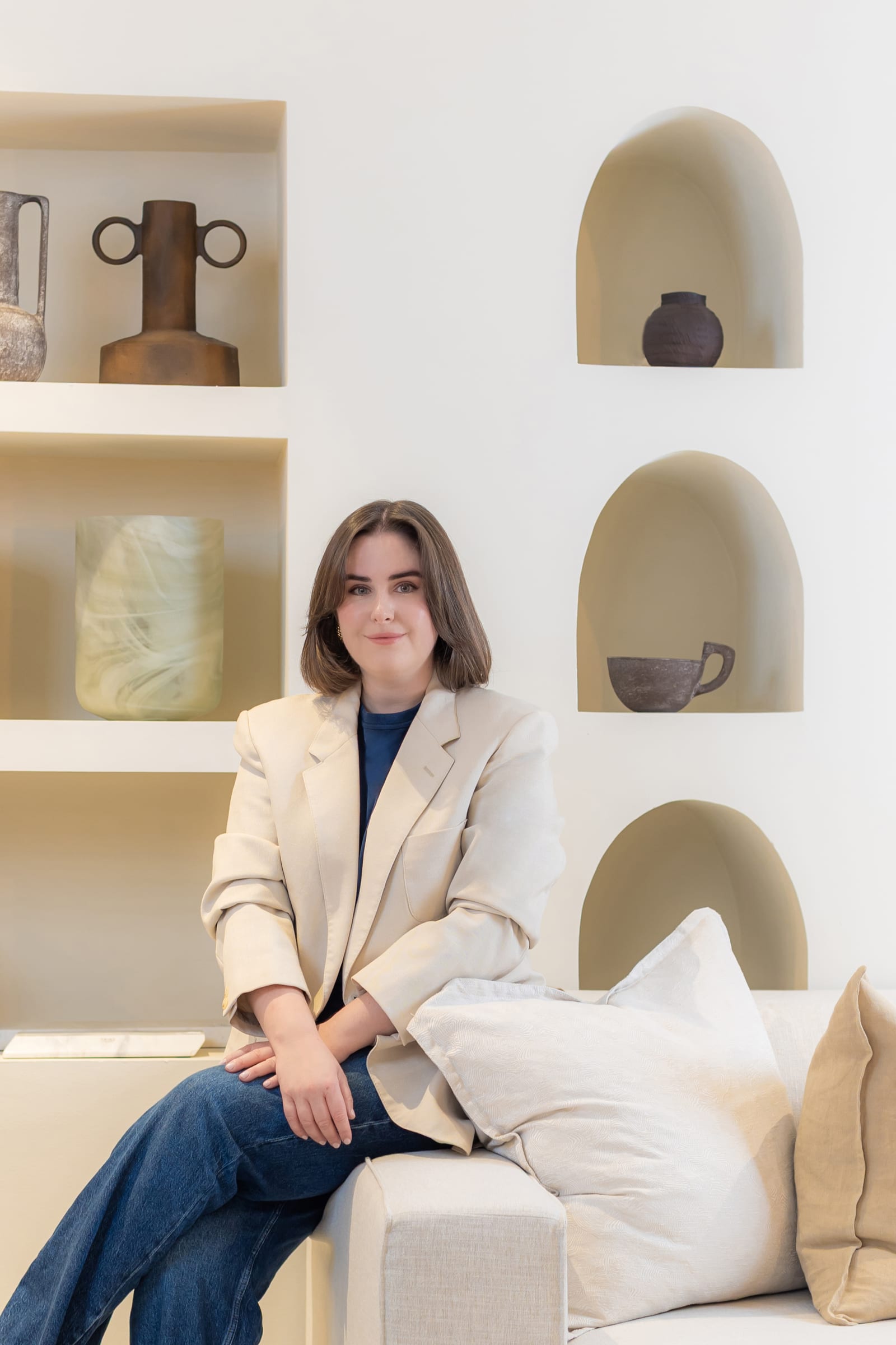 Emilie seated in front of arched niches holding ceramics