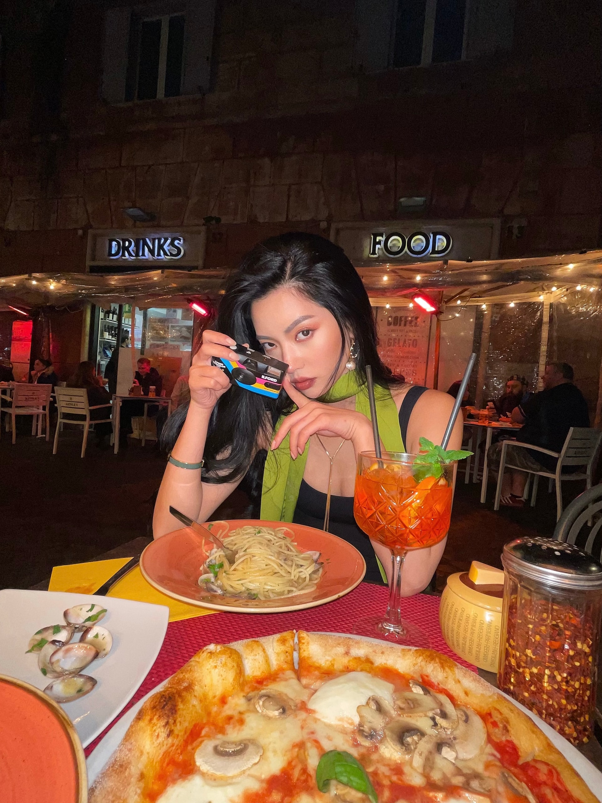Vailey with her film camera over pasta and a spritz