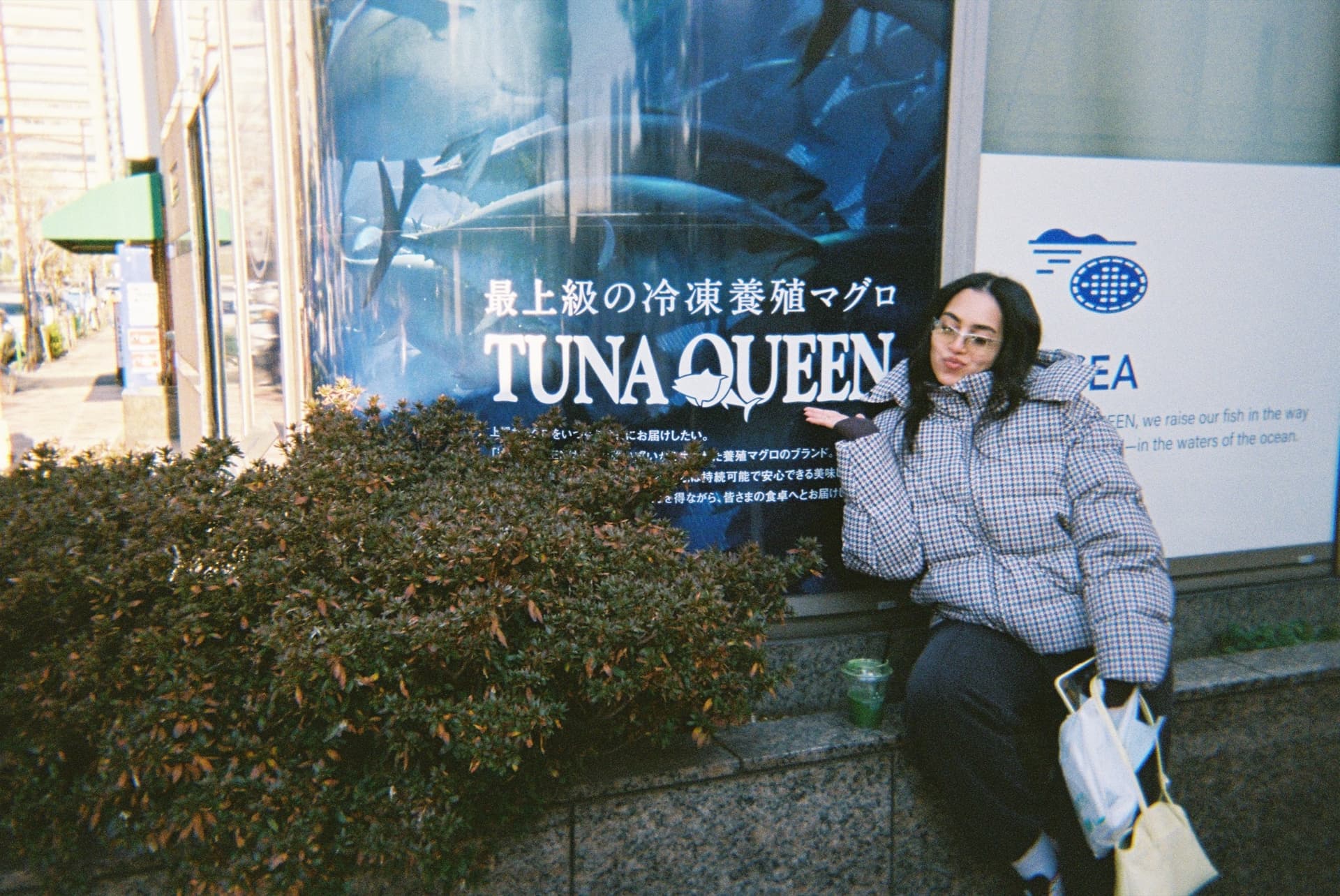 Nada on film, posing under a Tuna Queen sign in Japan