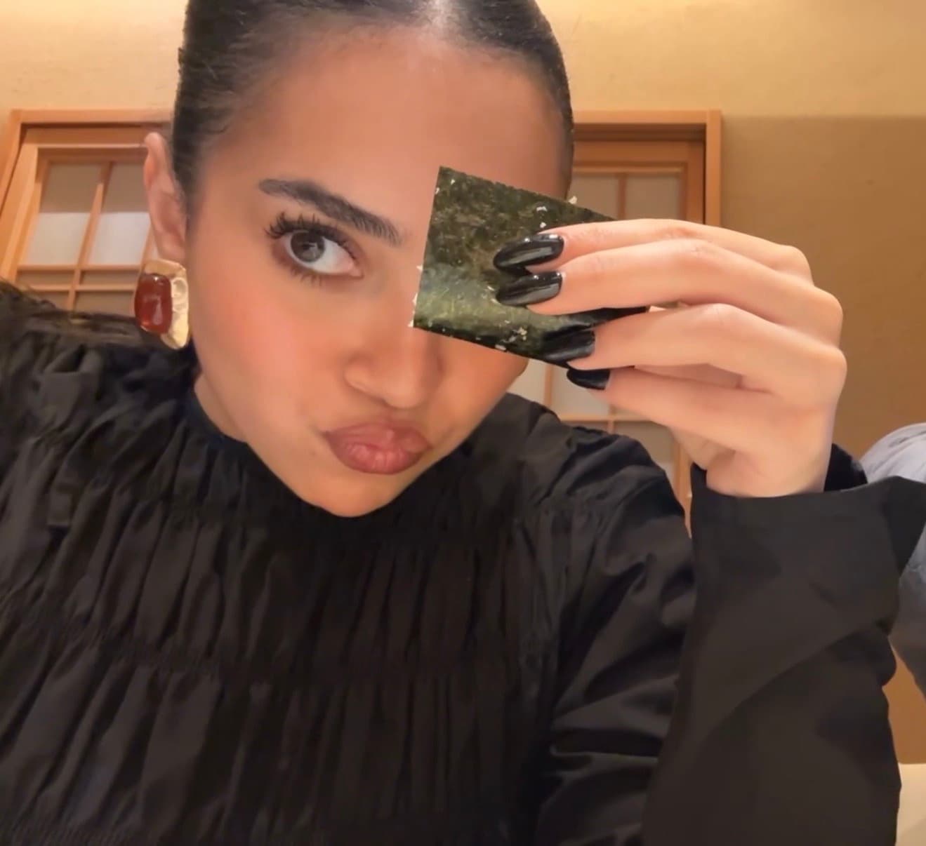 Nada holding a sheet of nori over one eye