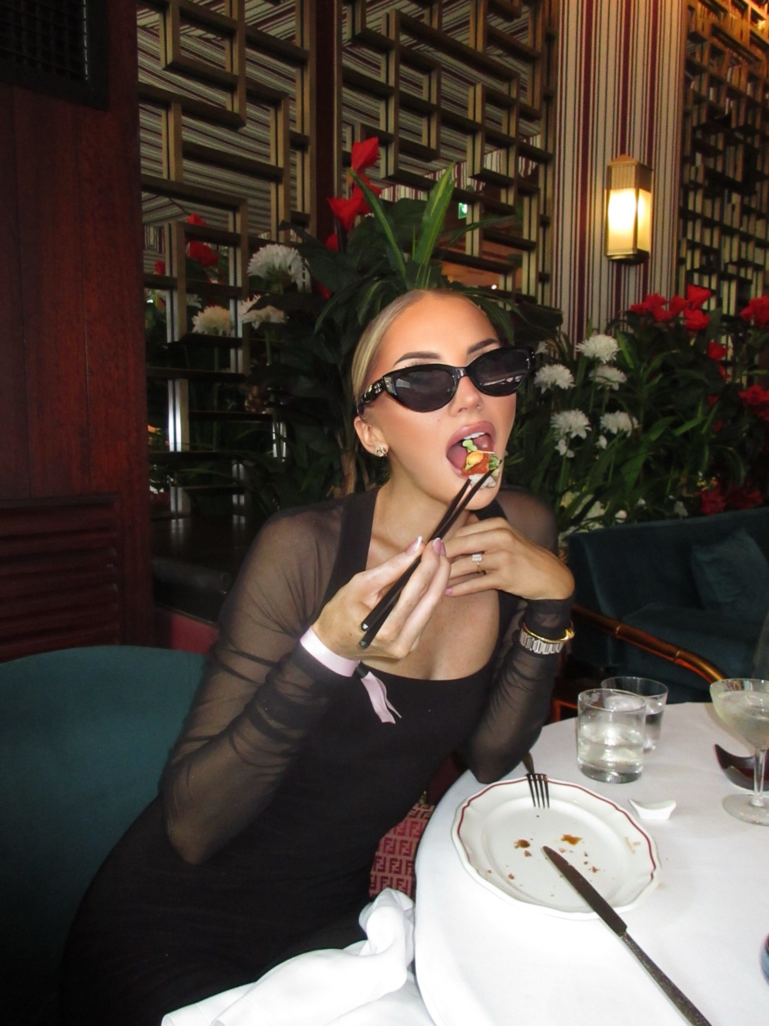 Orla mid-bite with chopsticks, sunglasses on