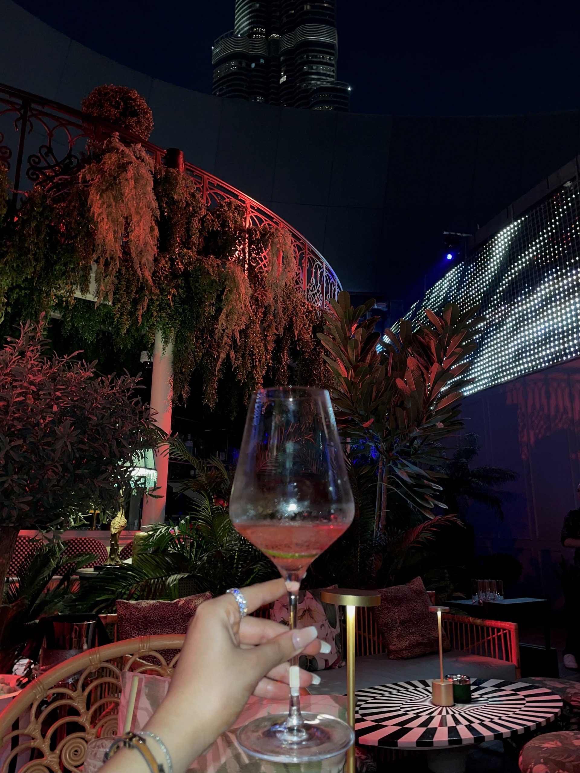 A glass raised to the Burj Khalifa from a rooftop table