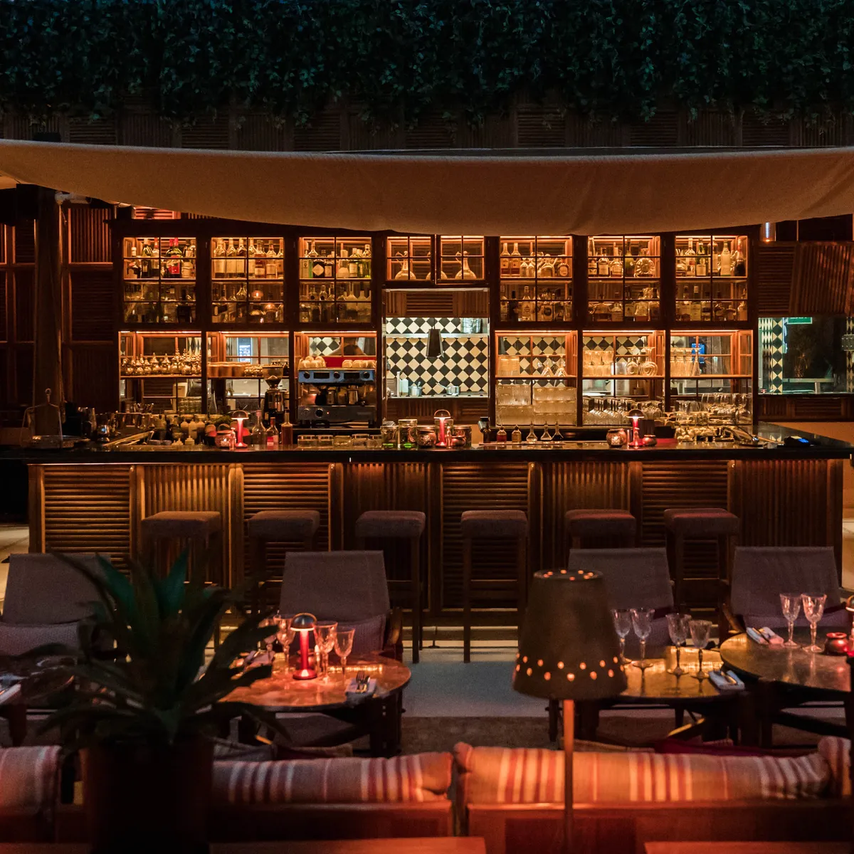 Ninive's bar under the canopy, bottles lit along its shelves