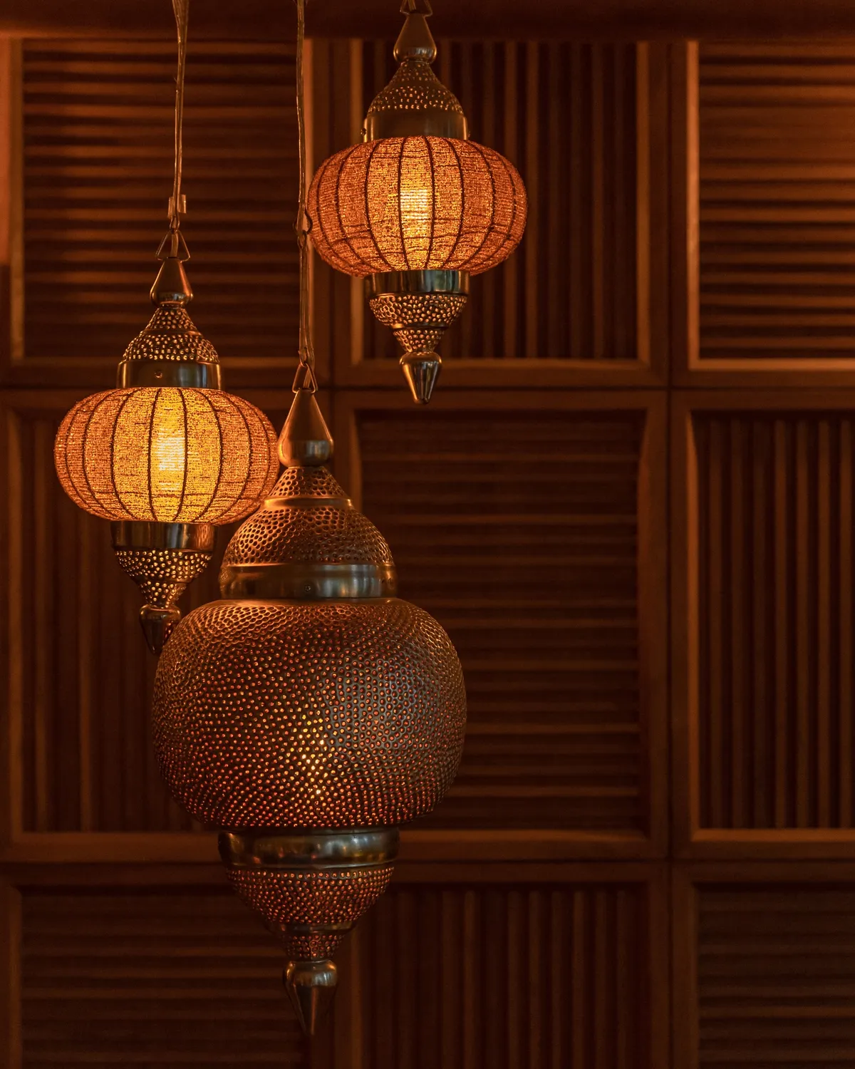 Brass lanterns hanging against Ninive's timber screens