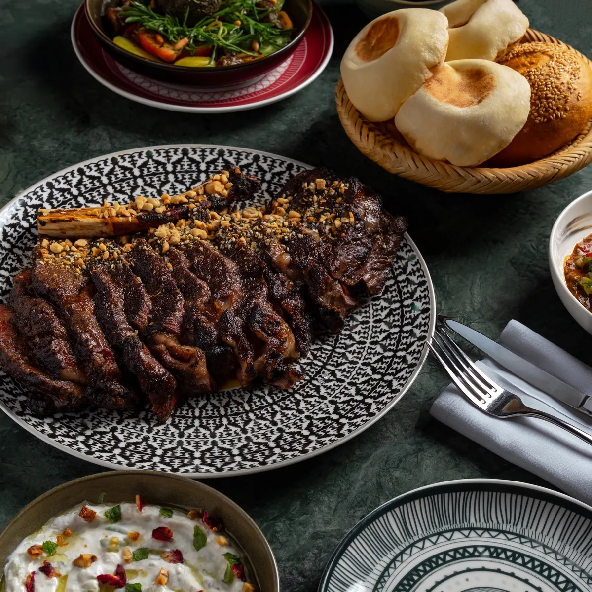 Grilled meats on a patterned platter with bread and dips, made to share