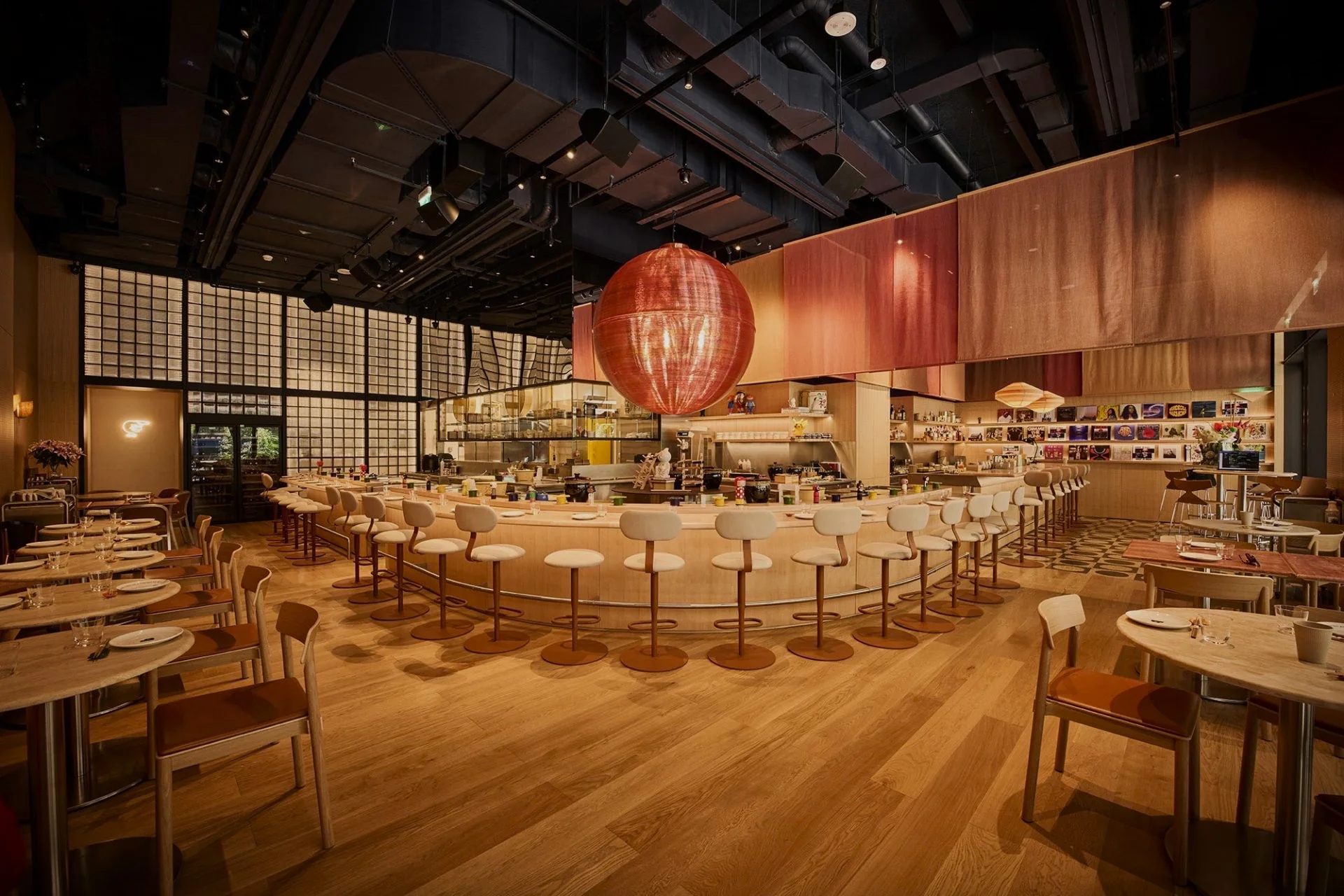 YUBI's dining room before service: white stools around the long curved counter, a giant red lantern hanging above it and record sleeves lining the far wall
