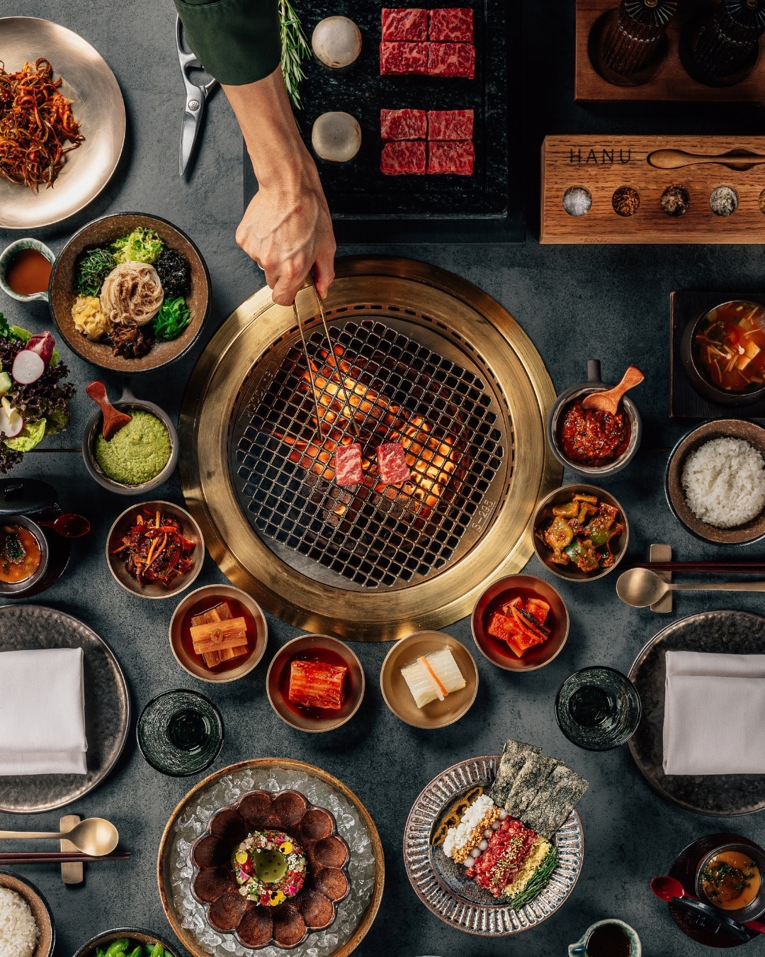 Banchan crowding the table grill at HANU