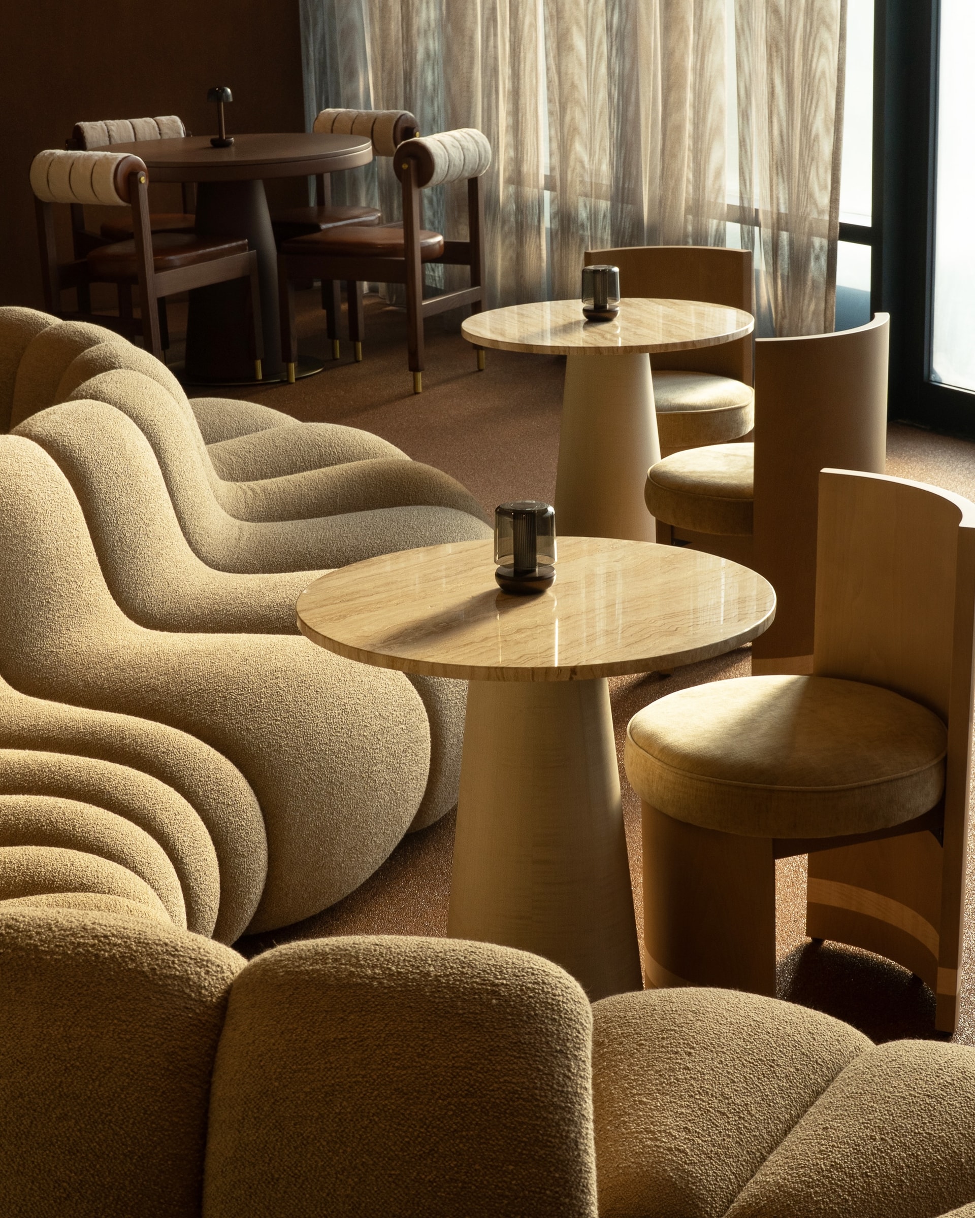 Curved bouclé sofas around a stone table at TRIO